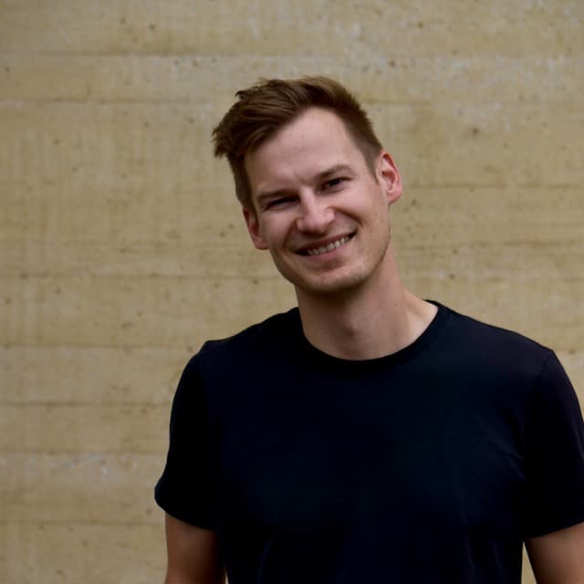 CEO portrait, smiling, in front of a concrete wall.