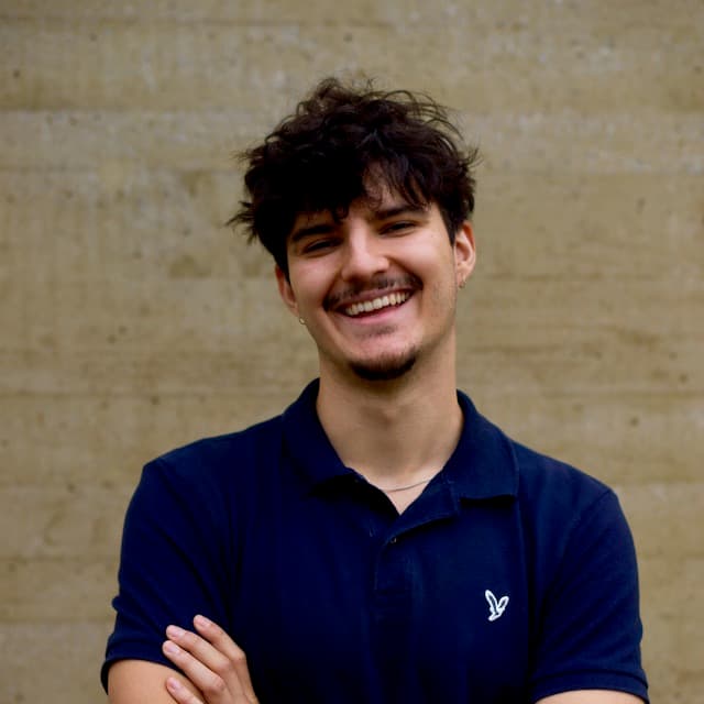 CTO im Porträt, mit verschränkten Armen, vor einer Betonwand, lächelnd.